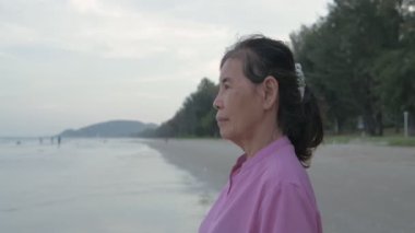 Seyahat konsepti 4k Çözünürlük. Asyalı yaşlı bir kadın kumsalda mutlu bir şekilde nefes alıyor..