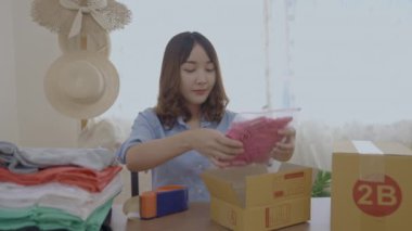 4k Kararlılığın iş konsepti. Asyalı kadın evdeki kutularda ürünleri paketliyor..