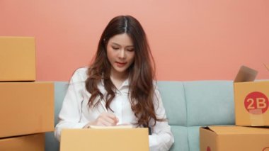 4k Kararlılığın iş konsepti. Asyalı kadın evde müşteri siparişlerini kontrol ediyor. belge kaydı. bir ürün listesi hazırlamak.