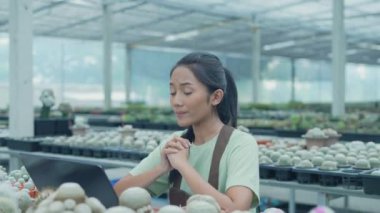 4k Kararlılığın iş konsepti. Dükkan sahibi bir bilgisayar kullanarak kaktüs satıyor. Asyalı kadın bir ağacı tanıtıyor. çevrimiçi ürün satmak.