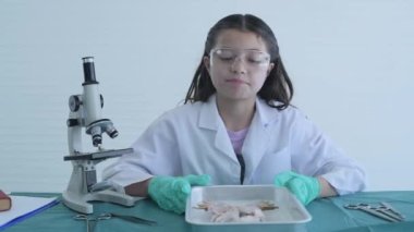 Eğitim konsepti 4k Kararlılık. Genç bir kız laboratuarda yapılan bir deneyi anlatıyor. Kurbağaların iç organlarını incelemek. röportaj medyası.