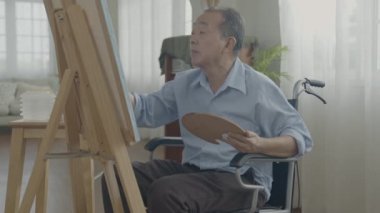 Sanatçı konsepti 4k Çözünürlük. Asyalı adam oturma odasında resim yapıyor. Sanatçı iş yaratıyor. Boş zaman aktiviteleri ve hobileri.