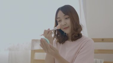 4k Çözünürlük 'ün güzellik konsepti. Asyalı kızlar yatak odasındaki yatakta makyaj yaparlar..