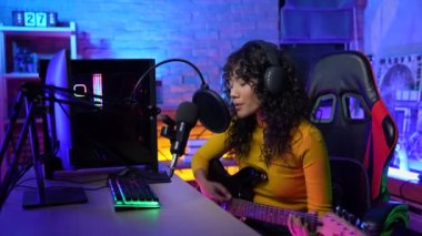 Yayınlanan 4k Çözünürlük kavramı. Asyalı kadın gitar çalıyor ve bilgisayarla kayıt yapıyor. canlı yayın.