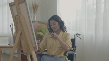 Sanatçı konsepti 4k Çözünürlük. Asyalı kadın oturma odasında resim çiziyor. Sanatçı iş yaratıyor. Engelli insanlar hobi yaratıyor..