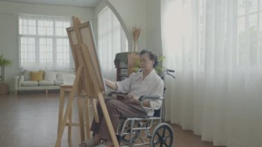 Sanatçı konsepti 4k Çözünürlük. Asyalı kadın oturma odasında resim çiziyor. Sanatçı iş yaratıyor. Engelli insanlar hobi yaratıyor..
