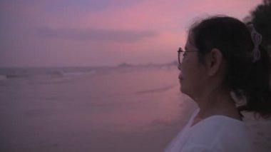 Seyahat konsepti 4k Çözünürlük. Asyalı yaşlı kadın sahilde dinleniyor..