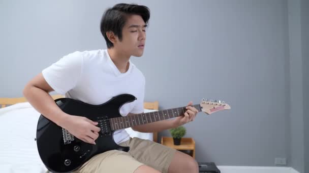 Konsep Holiday Resolusi Pria Asia Berlatih Gitar Listrik Kamar Tidur — Stok Video