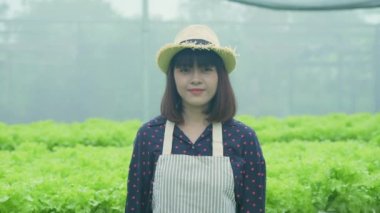 4k Çözünürlük Tarım Konsepti. Asyalı bir kadın, bir kreşteki bitkilerle ilgilenirken özgüvenle gülümsüyor..