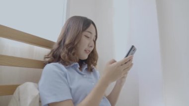 Tatil konsepti 4k Çözünürlük. Asyalı kızlar yatak odasında cep telefonu oynuyorlar..