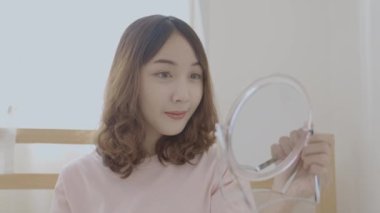 Tatil konsepti 4k Çözünürlük. Genç Asyalı kadın saçını yatak odasında tarıyor..