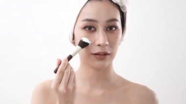 Spa konsepti 4k Çözünürlük. Asyalı kadın yatak odasında yüz kremi sürüyor. Çamur maskeli. yeşil çay özü.