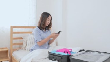 Tatil konsepti 4k Çözünürlük. Asyalı kız bavullarını bavula koyuyor. Tatil seyahatine hazırlanmak.