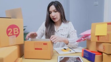 4k Kararlılığın iş konsepti. Asyalı kadın evdeki kutularda ürünleri paketliyor..