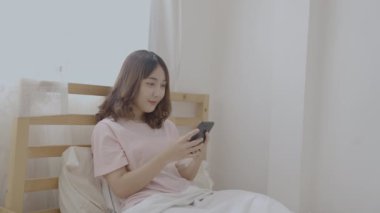 Tatil konsepti 4k Çözünürlük. Asyalı kızlar yatak odasında cep telefonu oynuyorlar..