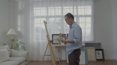 Artist concept of 4k Resolution. Asian man painting in the living room. Artist is creati