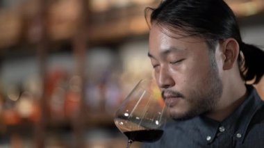 Gece kulübü konsepti 4k Kararlılık. Asyalı bir adam restoranda şarap tadıyor. Alkollü içecekler satan bir grup özel kulüp..