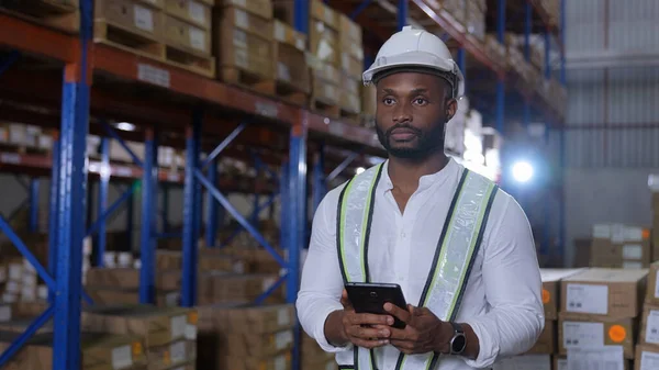 Business concept of 4k Resolution. African man checking goods in warehouse. Data collection of imported products from abroad.