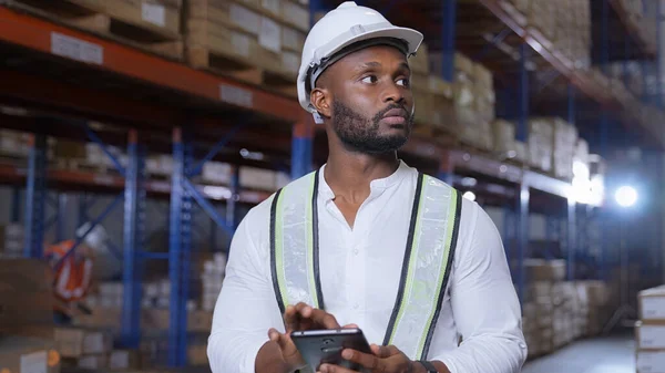 Business concept of 4k Resolution. African man checking goods in warehouse. Data collection of imported products from abroad.