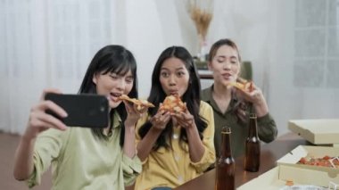 Tatil konsepti 4k Çözünürlük. Asyalı bir grup bayan arkadaş, çevrimiçi arkadaşlarını pizza yemeye davet ediyor. Eğlenceli ve heyecan verici eğlence aktiviteleri.