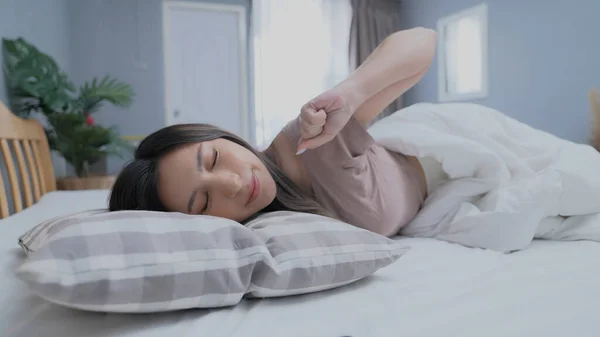 Holiday concept of 4k Resolution. Asian girls don\'t want to get out of bed in the morning. Mobile phone alarm. Laziness in waking up.