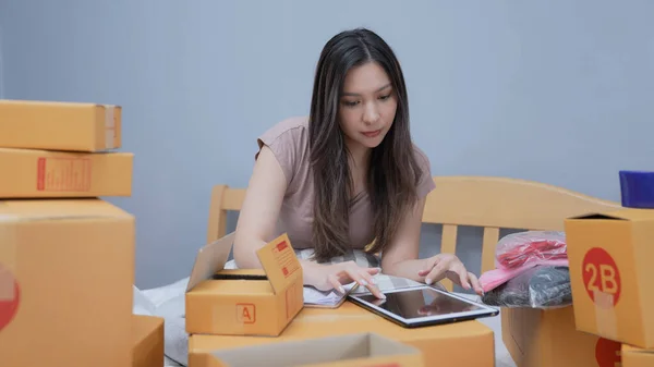 Business concept of 4k Resolution. Asian woman packing products in boxes at home. Delivery of products to customers through the post office.