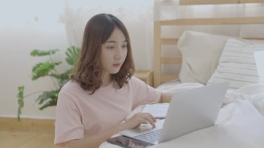 Tatil konsepti 4k Çözünürlük. Yatak odasında bilgisayarla çalışan Asyalı kızlar..