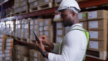4k Kararlılığın iş konsepti. Afrikalı adam depoda malları kontrol ediyor. Yurtdışından ithal ürünlerin veri koleksiyonu.
