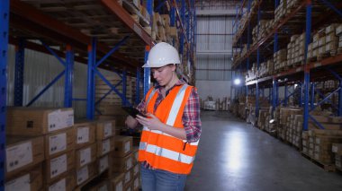 4k Kararlılığın iş konsepti. Bir çalışan depoda tabletle malları kontrol ediyor..
