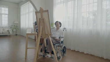 Sanatçı konsepti 4k Çözünürlük. Asyalı kadın oturma odasında resim çiziyor. Sanatçı iş yaratıyor. Engelli insanlar hobi yaratıyor..