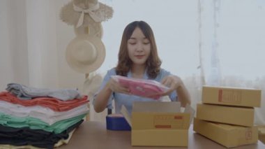 4k Kararlılığın iş konsepti. Asyalı kadın evdeki kutularda ürünleri paketliyor..