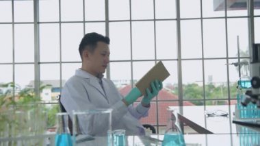 Research concept of 4k resolution. Asian scientists are searching for information from notebooks in the lab.