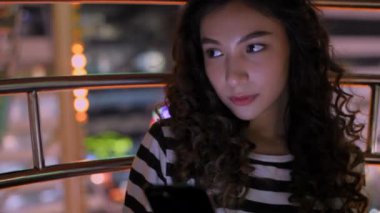 4k Kararlılığın Turizm konsepti. Dönme dolapta cep telefonuyla oynayan güzel bir kız..