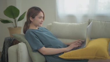 Hamile kadın konsepti 4k Kararlılık. Asyalı kızlar evde bilgisayar kullanarak çalışıyorlar..