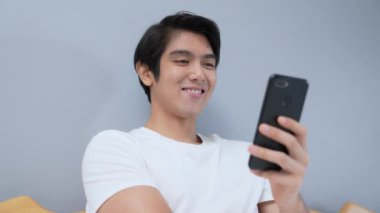 Tatil konsepti 4k Çözünürlük. Genç Asyalı adam yatak odasında cep telefonu çalıyor. iletişim teknolojisi.
