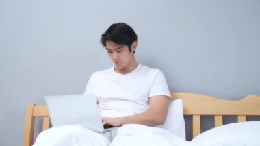 Tatil konsepti 4k Çözünürlük. Genç Asyalı adam yatak odasında çalışıyor..