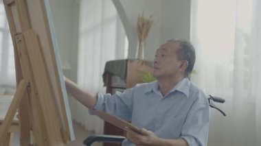 Sanatçı konsepti 4k Çözünürlük. Asyalı adam oturma odasında resim yapıyor. Sanatçı iş yaratıyor. Boş zaman aktiviteleri ve hobileri.