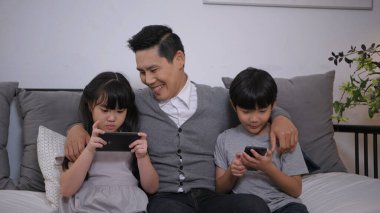 Family concept of 4k Resolution. Asian parents and children playing with mobile phones in the living room