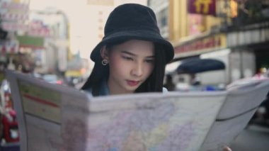 Seyahat konsepti 4k Çözünürlük. Asyalı kadınlar şehirde yer bulmak için haritalar kullanıyorlar..