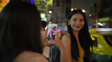 Travel concept of 4k Resolution. A beautiful girl is taking pictures on the pedestrian street at night.