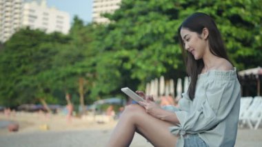 Holiday concept of 4k Resolution. Asian woman working using tablet at the beach.