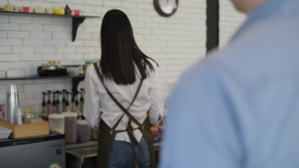 4K解像度のコーヒーショップのコンセプト バリスタが店内のお客様にコーヒーマグカップをお届けしています — ストック動画