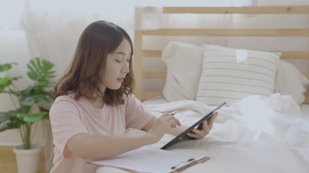 假日4K解像度的概念 亚洲女人在卧室里玩平板电脑 — 图库视频影像