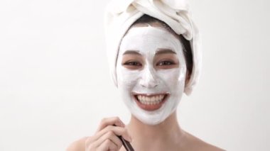 Spa konsepti 4k Çözünürlük. Asyalı kadın beyaz arka planda yüz spa tedavisi uyguluyor. Çamur maskeli. yeşil çay özü.