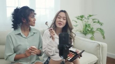Tatil konsepti 4k Çözünürlük. Asyalı kadınlar evde birlikte makyaj öğretiyor. Nüfuz Edici kozmetik ürünler öneriyor.