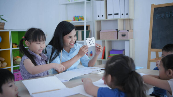 (Китайская формулировка transcape: insehr) Образовательная концепция 4k Resolution. Учитель учит детей учить китайский язык в классе.