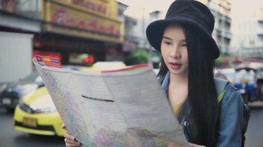 Seyahat konsepti 4k Çözünürlük. Asyalı kadınlar şehirde yer bulmak için haritalar kullanıyorlar..