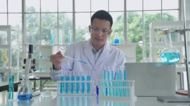 Araştırma konsepti 4K çözünürlüğü. Bir Asyalı test tüpüne sıvı damlatıyor..