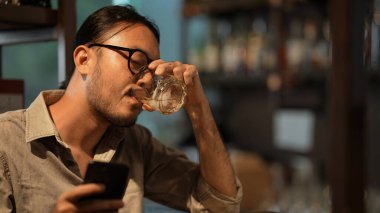 Gece kulübü konsepti 4k Kararlılık. Asyalı bir erkek müşteri içki dükkanında alkol içiyor. Alkollü içecekler satan bir grup özel kulüp..