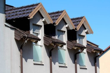 Üç sıra yenilenmiş eski tarz çatı penceresi üzerine koyu kahverengi kiremitler ve yeni boyanmış metal paratoner ile kaplanmış şeffaf camlı balkon kapakları yeni boyanmış metal oluk borularının yanında sevgili kısımlarında mahremiyet için.